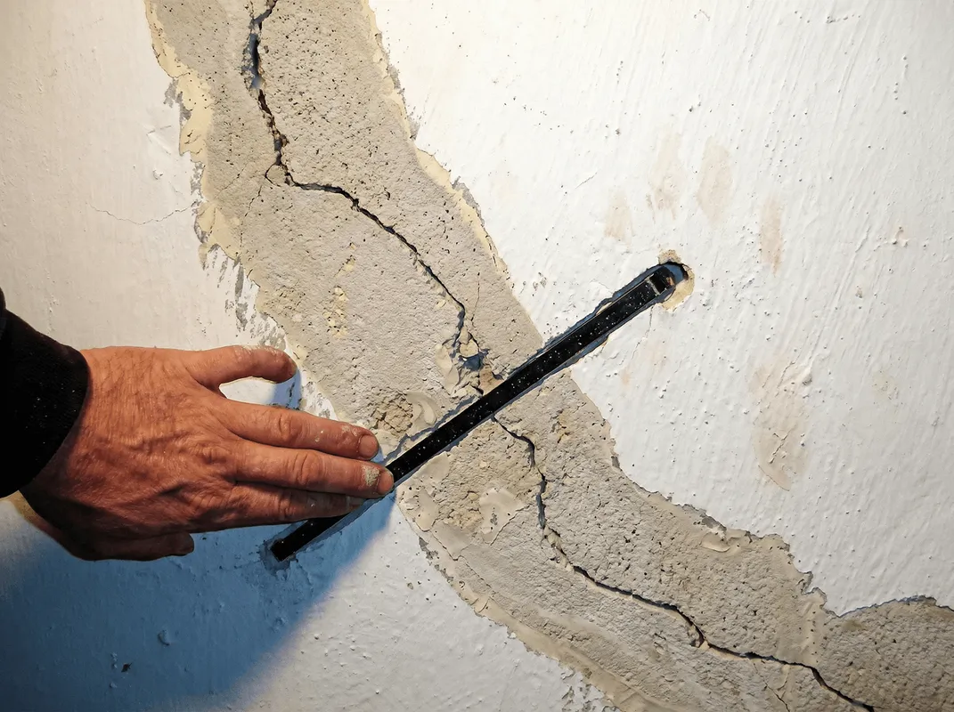 A wall with a large crack is being inspected by a professional in Portland, OR